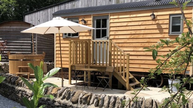 A wooden cabin with a deck, outdoor seating, and a stone wall. - Digby's Hut - sleeps 2 guests  in 1 bedroom (Foolow)