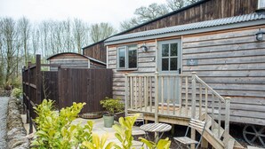 A wooden cabin with a deck, a small table, and a chair. - Digby's Hut - sleeps 2 guests  in 1 bedroom (Foolow)