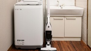 A compact, modern kitchen with a built-in washing machine, a sink, and a vacuum cleaner. - TAKETORI ROTEN (Beppu)
