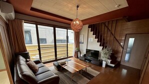 A modern living room with a sofa, coffee table, TV, and a staircase. - TAKETORI ROTEN (Beppu)