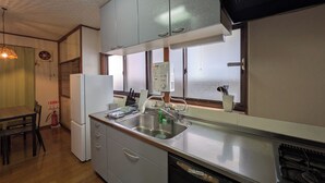 A compact kitchen with grey cabinets, a stainless steel sink, and a built-in dishwasher. - TAKETORI ROTEN (Beppu)