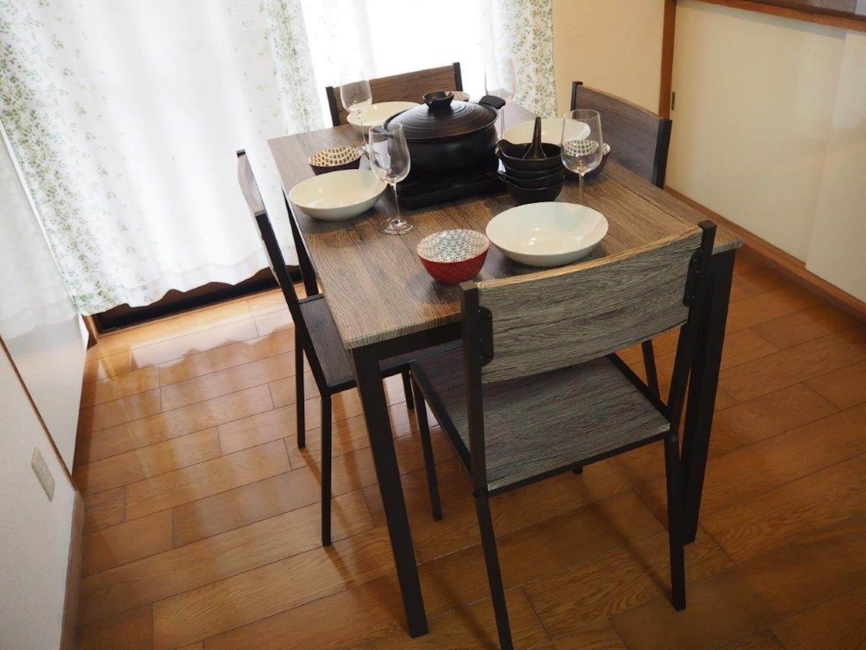 A dining table with chairs, a pot, bowls, and wine glasses.