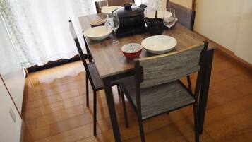 A dining table with chairs, a pot, bowls, and wine glasses.