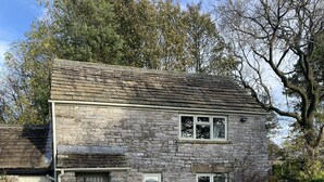 A stone house with a gravel driveway and a wooden table and chairs outside. - Brosterfield Cottage - sleeps 2 guests  in 1 bedroom (Foolow)