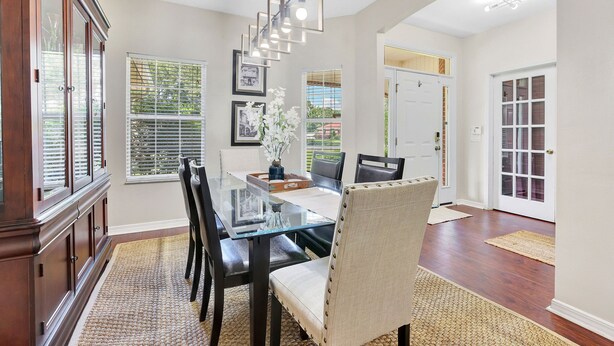 A dining area with a glass-top table, dark chairs, and a wooden cabinet. - Spacious 4 bedroom house by OWA & Tanger Outlets, 15 mins from Beaches (Foley)