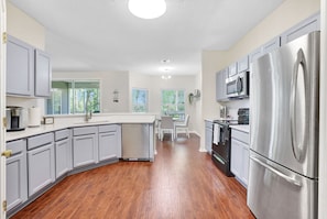 A modern kitchen with grey cabinets, stainless steel appliances, and a central island.