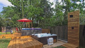 A backyard with a hot tub, a covered seating area, and a wooden deck. - Spacious 4 bedroom house by OWA & Tanger Outlets, 15 mins from Beaches (Foley)