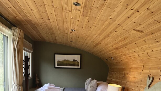 A cozy room with a bed, a sofa, a desk, and a window with curtains. - Hare’s Retreat - ( Middle Cabin )  - sleeps 2 guests  in 1 bedroom (Foolow)