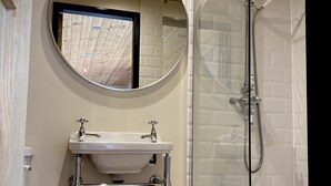 A bathroom with a round mirror, a sink, and a glass-enclosed shower. - Hare’s Retreat - ( Middle Cabin )  - sleeps 2 guests  in 1 bedroom (Foolow)