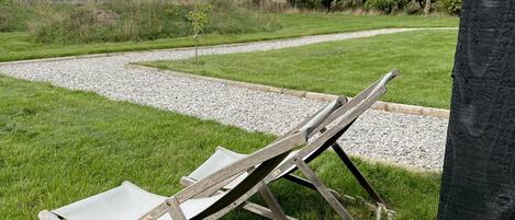 A grassy area with two wooden folding chairs and a gravel path.