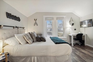 Relax in a spacious bedroom with a large bed, desk, and window view.