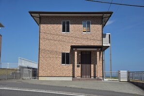 A two-story brick building with a flat roof, a gated entrance, and a small porch area. - Bep one (Beppu)