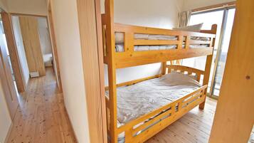A bunk bed in a room with wooden flooring and a window.