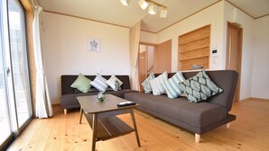 Ein Wohnzimmer mit einer Couch, einem Couchtisch und einem Fenster mit Vorhängen.