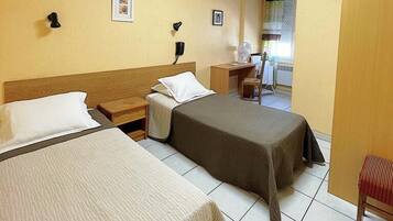 A hotel room with two beds, a desk, a chair, and a window with curtains.