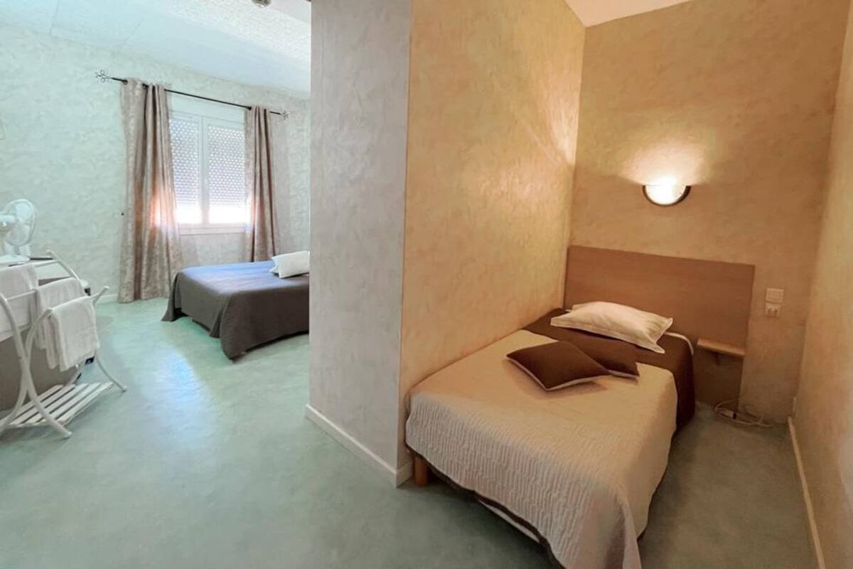 Une chambre d’hôtel avec un lit, une table de chevet, une lampe et une fenêtre avec des rideaux.