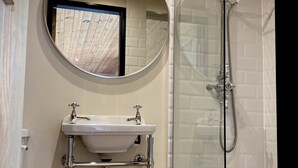 A bathroom with a round mirror, a sink, and a glass-enclosed shower. - Robin’s Nest - ( Top Cabin )  - sleeps 2 guests (Foolow)