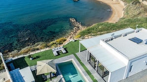 A modern house with a rooftop pool, a patio with outdoor furniture, and a view of the sea. - Villa Sabbie Rosse 6 2 (Isola di Capo Rizzuto)