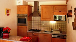A kitchen with wooden cabinets, a stove, oven, microwave, and a sink. - Studio cabin Valloire 4 pers South - Pets allowed, Wifi (Valloire)