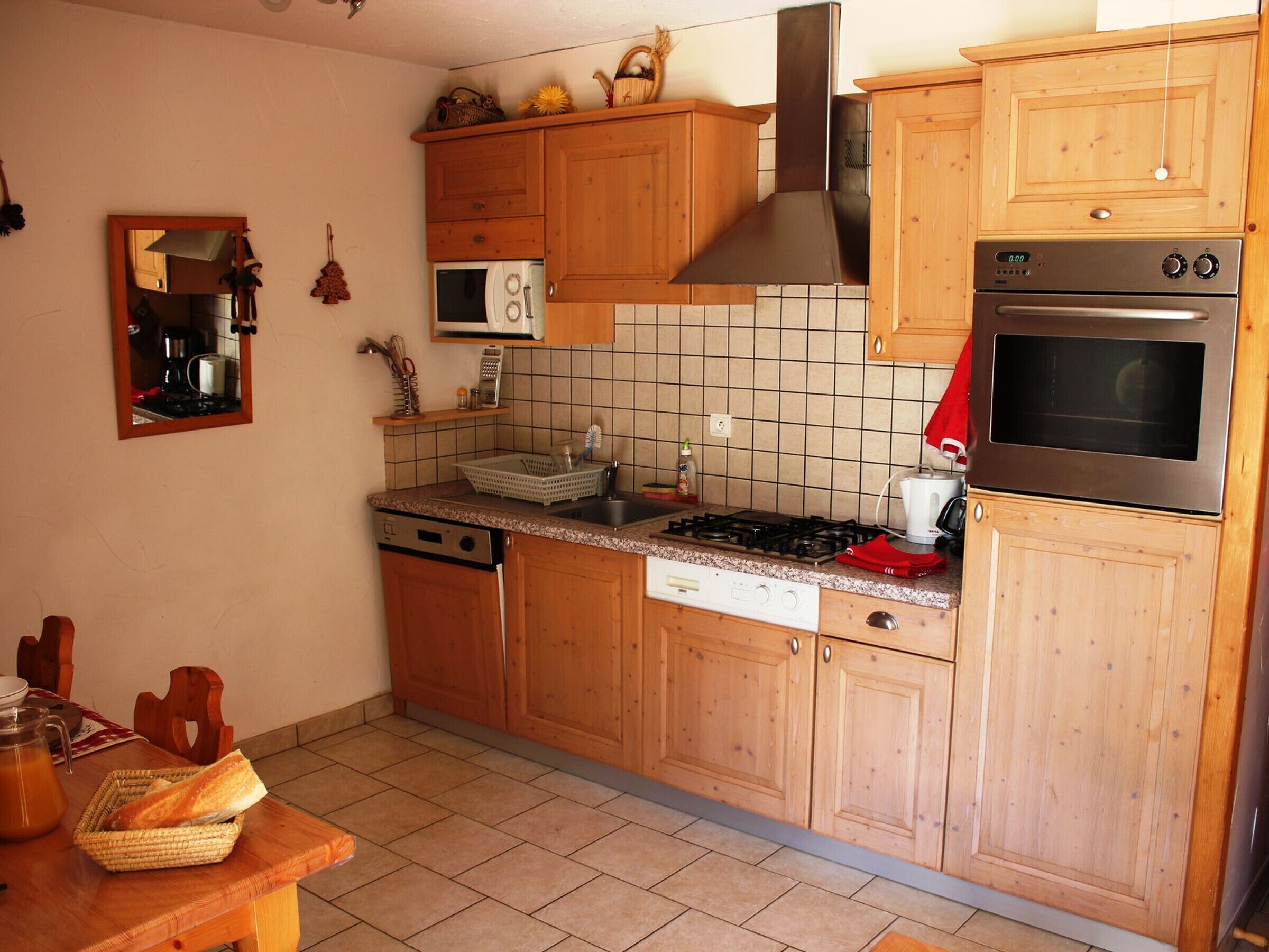 A kitchen with wooden cabinets, a stove, an oven, a microwave, and a dishwasher.