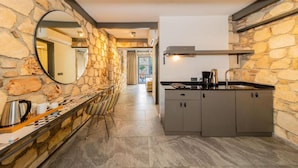 A kitchen with stone walls, a bar area with chairs, and a sink. - Alp Pasa Fiore Garden Suites - Special Class (Antalya)