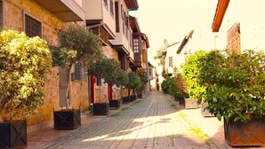 A cobblestone street lined with traditional buildings, some with balconies and potted plants. - Alp Pasa Fiore Garden Suites - Special Class (Antalya)