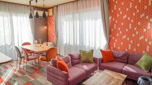 Ein modernes Wohnzimmer mit einer Couch, Sesseln, einem Esstisch und einer Wand mit Muster.