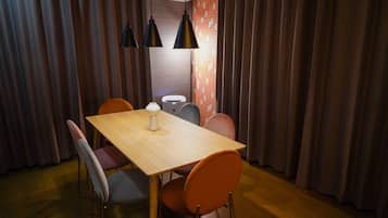A dining area with a wooden table, orange chairs, and black pendant lights.