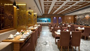 A modern restaurant with a long dining area, wooden ceiling, and decorative wall panels. - Cygnett Park BL (Jaipur)