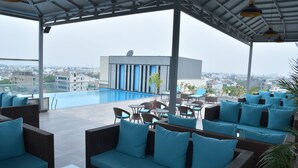 A rooftop lounge with a pool, outdoor seating, and a view of the cityscape. - Cygnett Park BL (Jaipur)