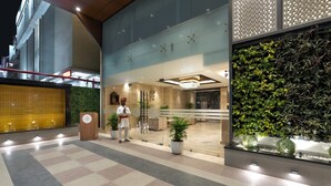 A hotel entrance with a reception desk, a wall-mounted clock, and a potted plant. - Cygnett Park BL (Jaipur)