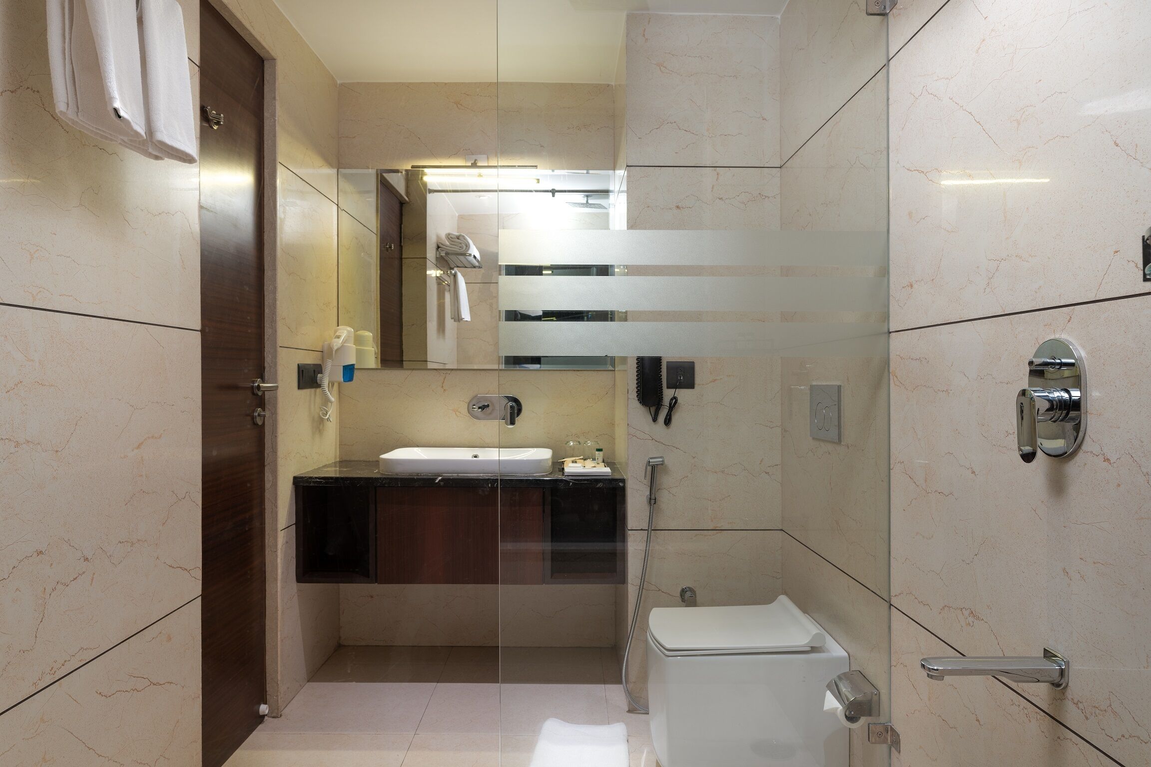 Ein modernes Badezimmer mit einer gläsernen Duschkabine, einem weißen Waschbecken und einer Toilette.