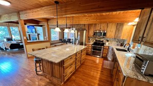Une cuisine spacieuse, dotée de meubles en bois, d’un grand îlot central et d’appareils électroménagers modernes.