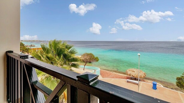 A balcony with a view of a turquoise sea and a clear sky. - Chachacha Apartment At Sea with spectacular views and dining with an ocean view (Kralendijk)
