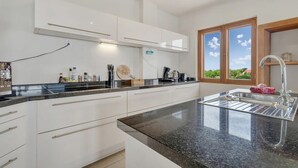 A modern kitchen with white cabinets, a granite countertop, and a stainless steel sink. - Chachacha Apartment At Sea with spectacular views and dining with an ocean view (Kralendijk)