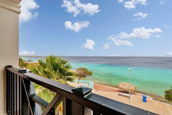A balcony with a view of the ocean and a beach.
