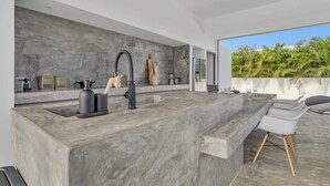 Cozinha moderna com uma ilha grande, forno embutido e vista para o verde lá fora.