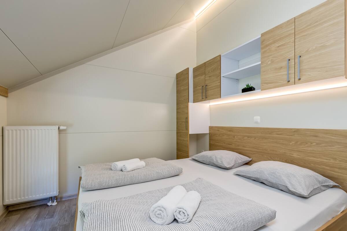Una habitación de hotel moderna con una cama grande, cabecero de madera y armarios empotrados.