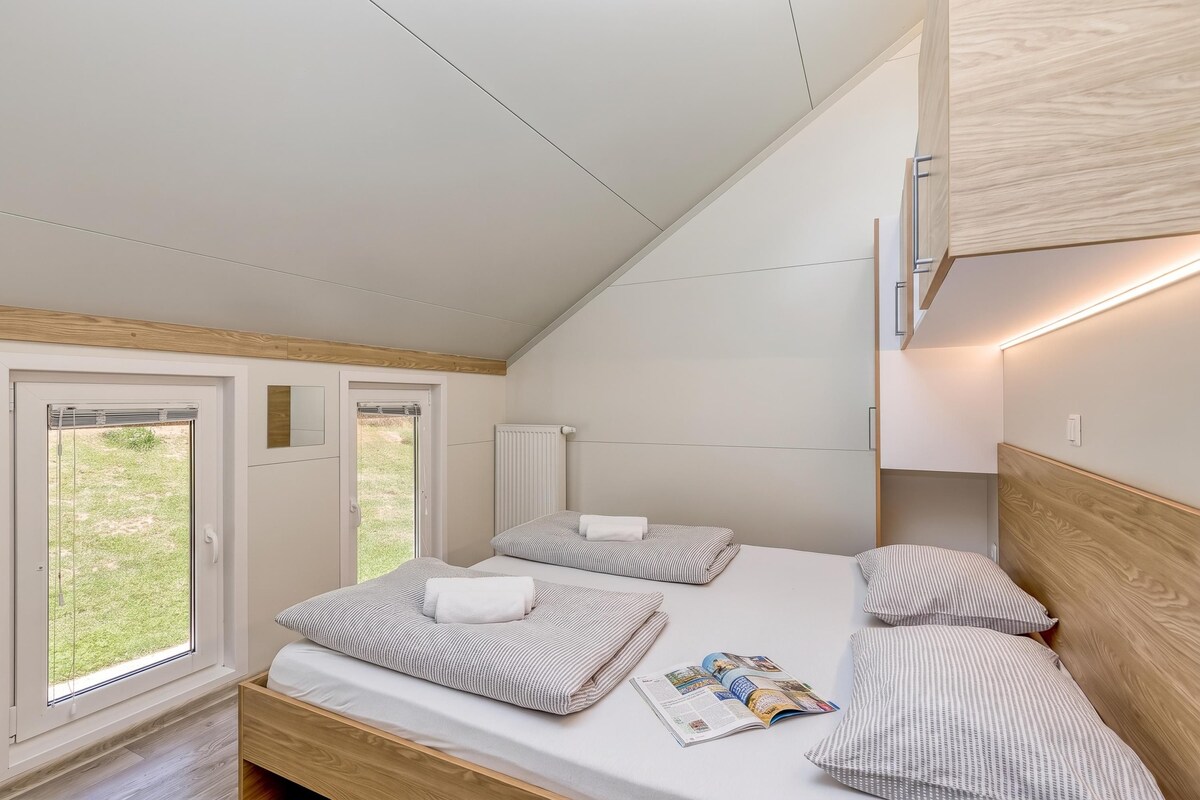 A bedroom with a bed, two bedside tables, a window, and a magazine on the bed.