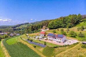 A rural house with solar panels, surrounded by fields and a river.