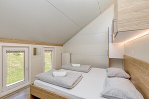 A bedroom with two beds, wooden headboards, and a view of the outdoors. - Pool & Whirlpool Art Villas (Trebnje)