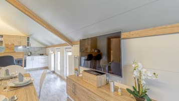 Una cocina moderna con armarios de madera, un televisor de pantalla plana grande y un comedor con mesa lista para dos.