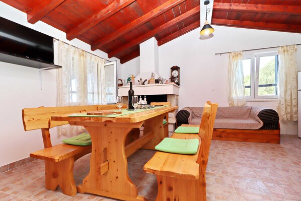 Una habitación acogedora con una mesa de madera, bancos, un sofá, una chimenea y una ventana.