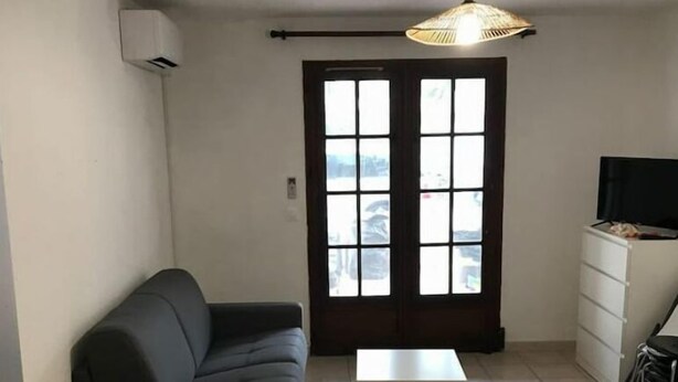 Una sala de estar con un sofá, una mesita, un televisor sobre un mueble bajo y una ventana con vistas.