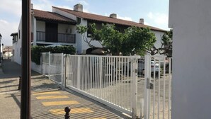 Un conjunto residencial cerrado con valla blanca, camino de entrada pavimentado y un edificio con tejado de tejas.