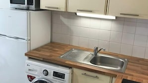Una cocina compacta equipada con lavadora, microondas y fregadero.