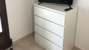 Un aparador blanco con un televisor de pantalla plana encima y un control remoto a su lado.