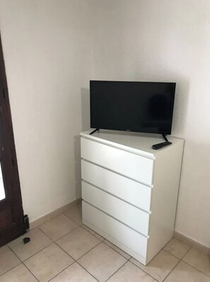 Eine weiße Kommode mit einem Flachbildfernseher darauf und einer Fernbedienung daneben.