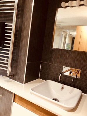 Een bad/douchecombinatie, een haardroger, handdoeken, zeep