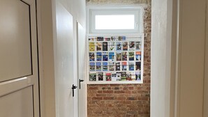 A hallway with a brick wall and a window above a bulletin board displaying various items. - Apartment Schloofschdubb in Fuldatal Nähe Kassel (Fuldatal)